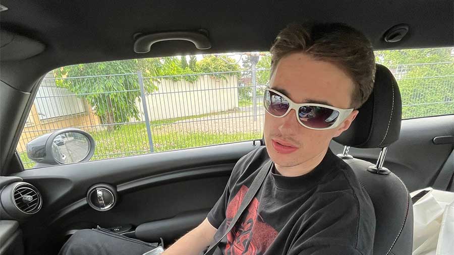 Junger Mann sitzt mit Sonnenbrille im Auto