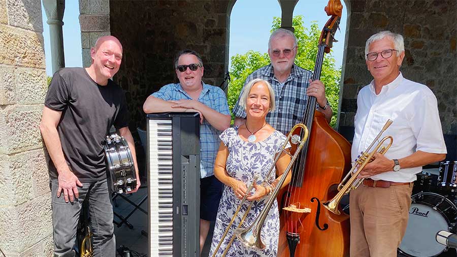 Vier Musiker mit Instrumenten und eine Sängerin im Freien