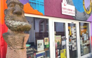 Statue vor Fensterfont des Café Krem